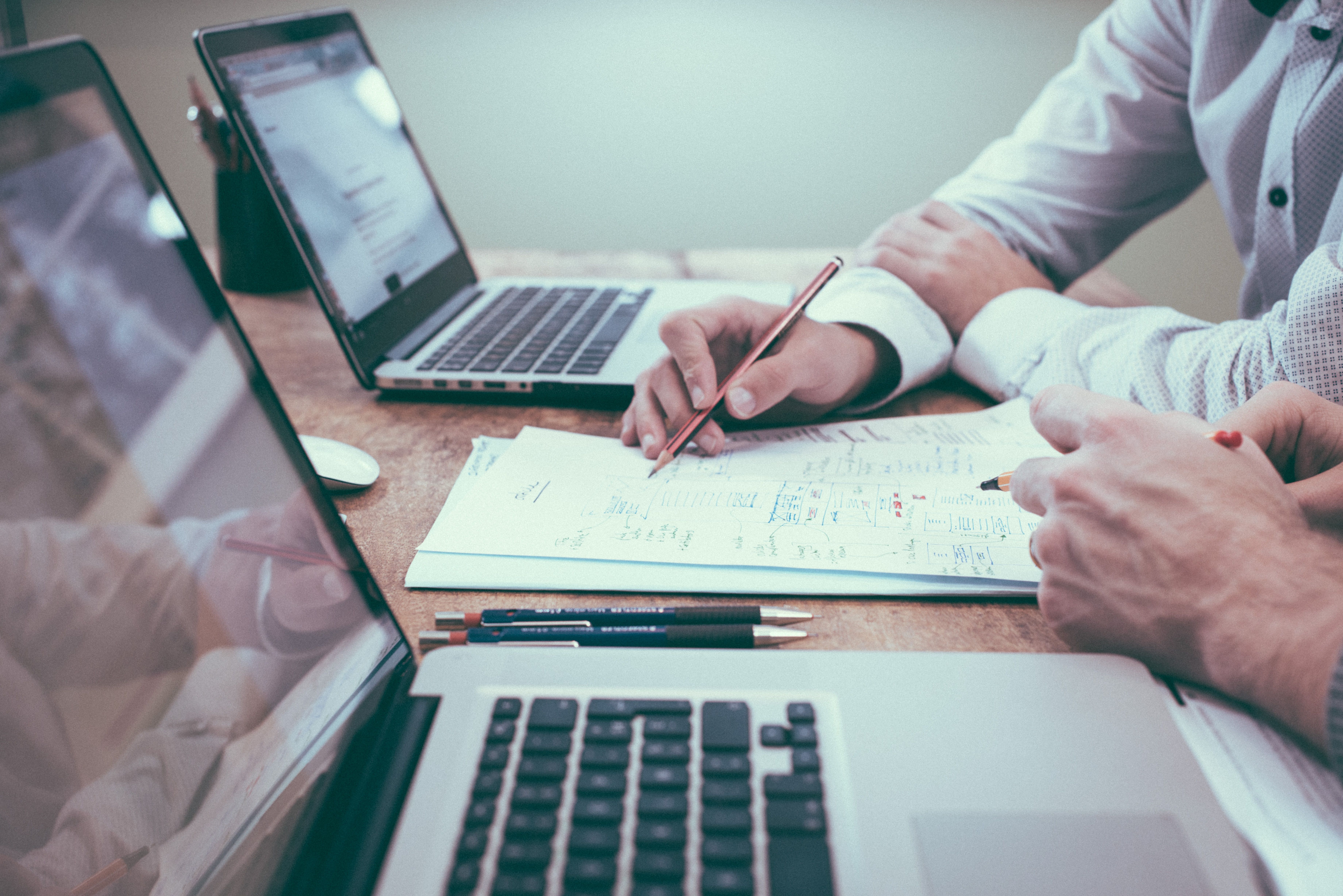 people consulting on paper between two laptops