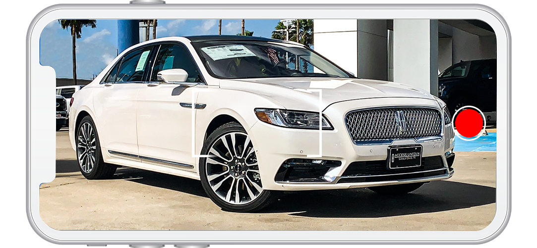 A white car viewed on a phone screen